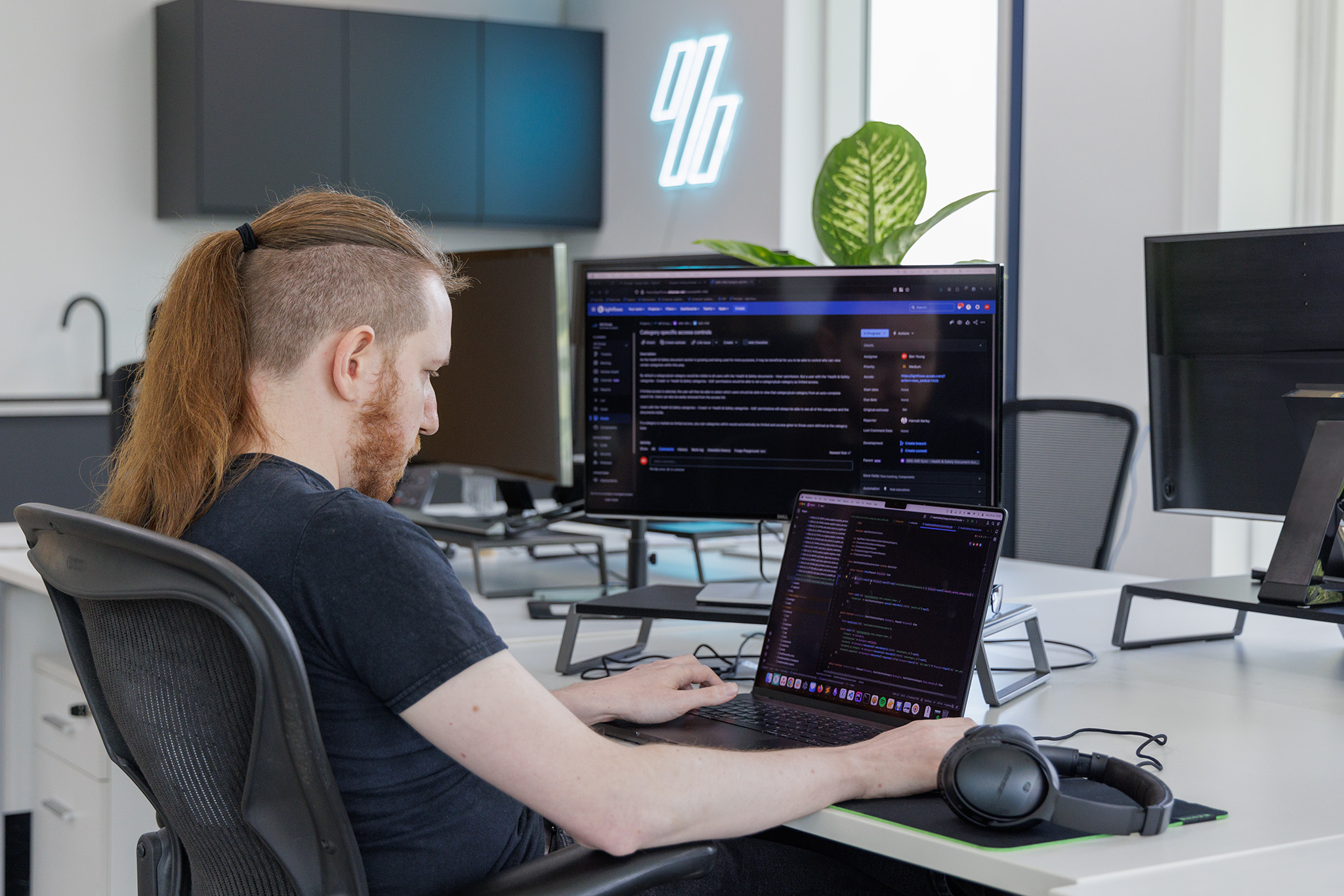 Picture of a web developer at a desk in a modern web development agency setting with two monitors working on code